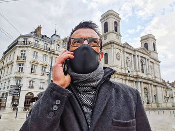 Portrait of man standing against building in city