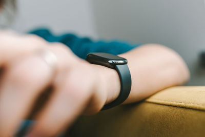 Cropped hand of woman wearing smart watch at home