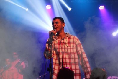 Young man with arms raised at music concert