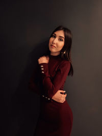 Portrait of a smiling young woman against black background