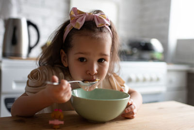 Portrait of cute baby girl sitting on table at home