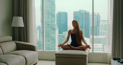 Young woman using phone while sitting on sofa at home