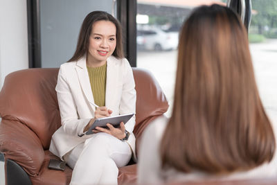 Young woman using smart phone while sitting in laptop