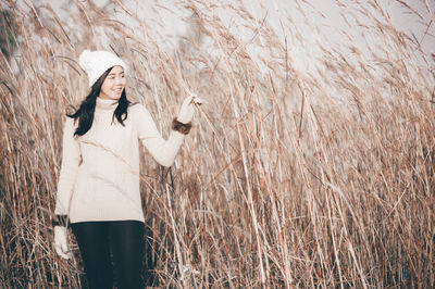 Young woman in warm clothing standing amidst plants on field