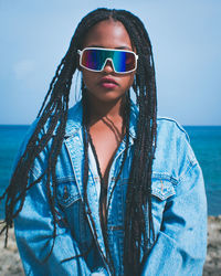 Portrait of young woman wearing sunglasses against blue sea