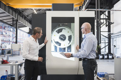 Two men looking at machine on factory shop floor