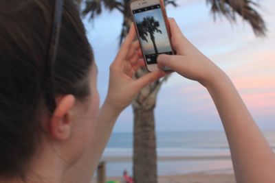 Portrait of woman photographing sea through camera