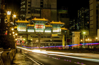 Light trails on city street by buildings at night