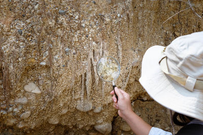 Cropped hand of woman standing on rock