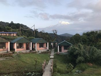 Houses by trees and buildings against sky