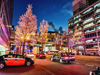 Cars on city street by buildings at night