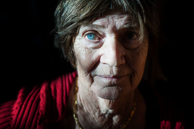 Close-up portrait of senior woman against black background