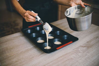 Close-up of cropped female hands preparing cupcakes