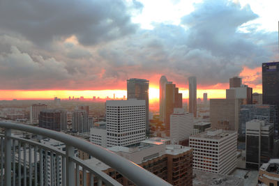 Modern buildings in city against sky during sunset