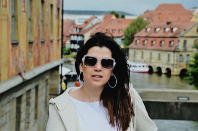 Portrait of woman wearing sunglasses against buildings in city