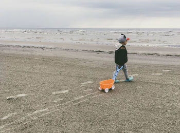 Boy pulling wagon while walking at beach