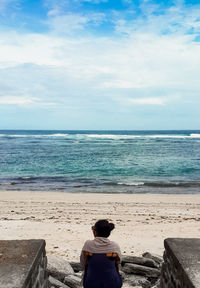 Rear view of woman sitting on beach