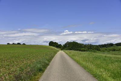 Scenic view of road amidst field against sky