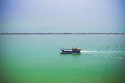 Boat sailing in sea against clear sky