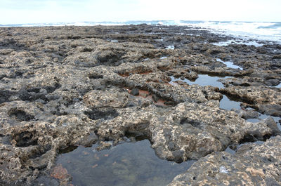 Rock formation on beach against sky