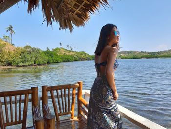 Woman standing by lake against sky