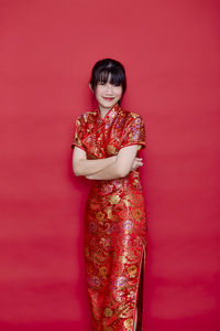 Portrait of smiling woman standing against red background