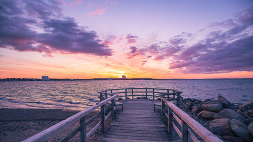 Pier over sea against sky during sunset