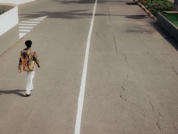 Rear view of man walking on road