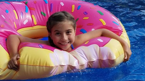 Portrait of smiling girl with inflatable donut in swimming pool