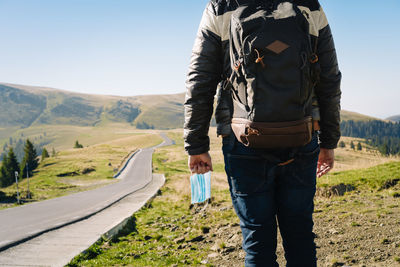 Rear view of man with mask standing on mountain road