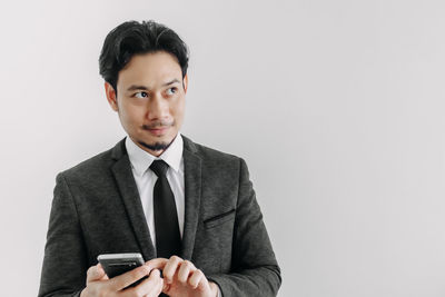 Portrait of young man using smart phone against white background