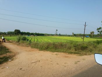 Road by field against clear sky