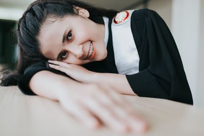 Portrait of smiling young woman leaning on table at home