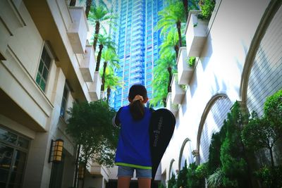 Low angle view of young woman standing against buildings in city