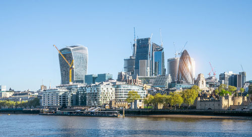 Modern buildings by river against sky in city