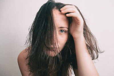 Portrait of young woman with messy hair against wall