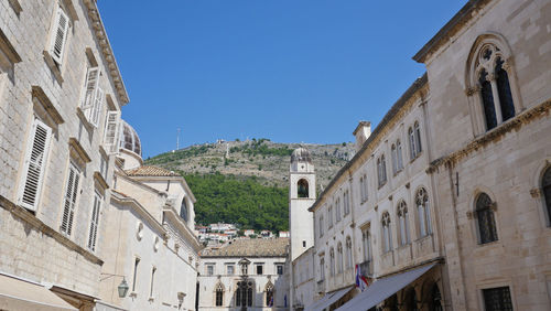 Low angle view of buildings in city against clear blue sky