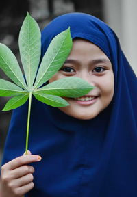 Close-up portrait of smiling girl holding blue face