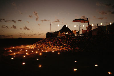 Bright glowing lamps illuminating area around street restaurant located among dark desert terrain during night in morocco