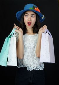 Portrait of woman wearing hat standing against black background