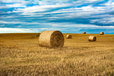 Hay bales on field against sky