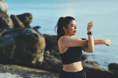 Side view of woman exercising at beach