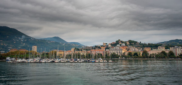 Sailboats in city by buildings against sky