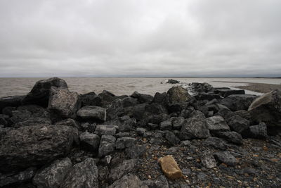 Rocks on sea shore against sky