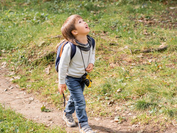 Little explorer on hike in forest. boy with binoculars, backpack and rope. outdoor leisure activity.