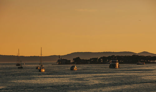 Silhouette sailboats in sea against clear sky during sunset