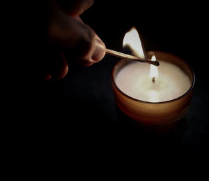 Close-up of hand lighting candle 