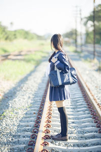 Side view of woman standing on railroad track
