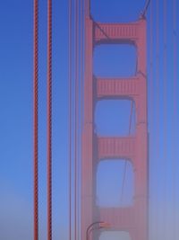 Low angle view of suspension bridge against blue sky