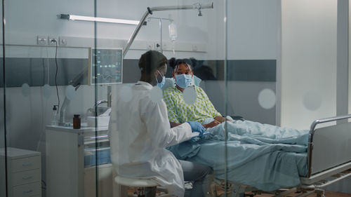 Rear view of doctor examining patient in hospital